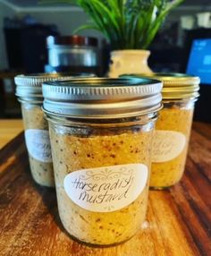 three jars filled with food sitting on top of a wooden table next to a potted plant