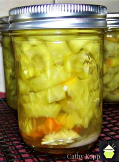 two jars filled with pickled vegetables sitting on a table