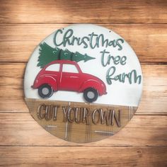 a christmas tree farm sign with a red car in the center on a wooden background