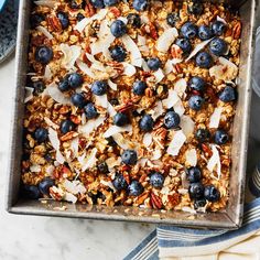 a pan filled with granola and blueberries on top of a table