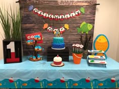 a blue table topped with cake and cupcakes