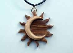 a wooden sun and moon hanging from a leather cord necklace on a white table top