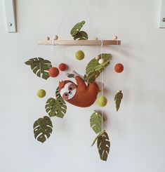 a stuffed slotty hanging from a wooden frame with leaves and balls on the wall