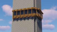 a tall brick tower with a balcony and balconies on the top, against a cloudy blue sky