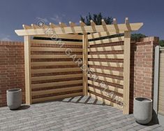 an open wooden gate on top of a brick patio next to a wall and two trash cans