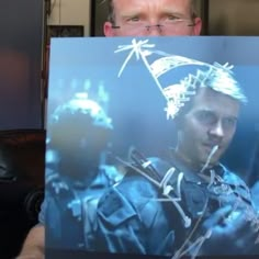 a man holding up a poster with an image of himself in the middle and behind him