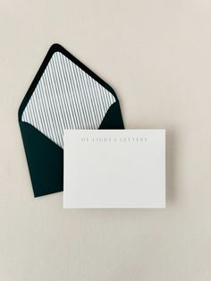 two envelopes with white and black paper on them, one has a note card attached to it