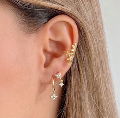 a close up of a woman's ear wearing gold earrings with flowers on them