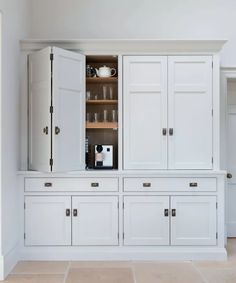 an empty kitchen with white cabinets and tile flooring on the walls, along with a coffee maker