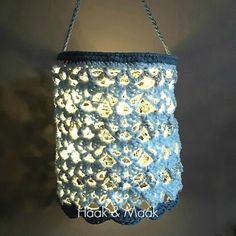 a crocheted blue and white bag hanging from a hook on a gray wall