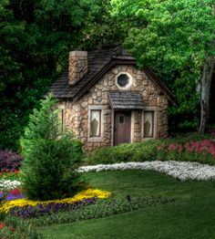 a small stone house surrounded by flowers and trees