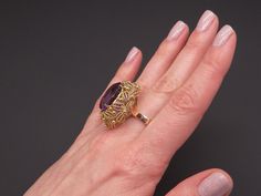 Jewelry Type: Ring Metal: 18k Yellow Gold Markings: 18k Measurements: 27mm x 24mm wide ( front face of ring) 3mm wide back of shank (most narrow area of band) 17mm high ( finger to top of ring) Weight: 15.1 grams Main Stone: Oval Cut Amethyst Gem Measurements: 17.7mm x 13mm x 11.7mm Gem Weight: 14ct total approx US Finger Size: 6 Video posted on our Instagram page @ CileoneJewelry #10358 Luxury Gold Oval Amethyst Ring, Gold Oval Amethyst Ring In Art Deco Style, Formal Oval Gold Amethyst Ring, 1970s Jewelry, Flower Band, Coral Flowers, Front Face, Love Anniversary, Amethyst Gem