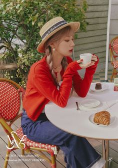 a woman sitting at a table drinking coffee and croissants