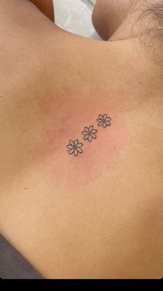 a woman's back with three small flowers on it