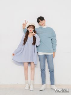 two people standing next to each other in front of a white wall with one person making the peace sign