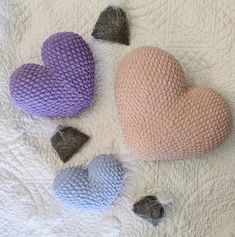 three knitted hearts on a white quilt