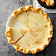 a pie sitting on top of a white plate next to a fork and spoons