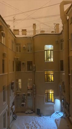 an alley way with snow on the ground and apartment buildings in the backround