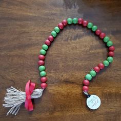 a red and green beaded necklace with a tasseled charm on a wooden table