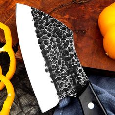 a large knife sitting on top of a cutting board next to oranges and a pair of scissors