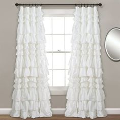 white ruffled curtains hanging in front of a window with a mirror on the wall