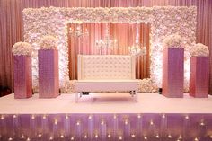 a white bench sitting in front of a purple and white stage with flowers on it