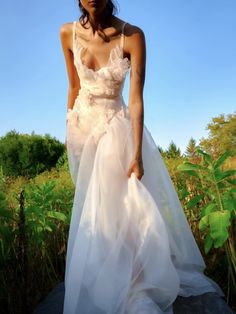 a woman in a wedding dress standing on a rock