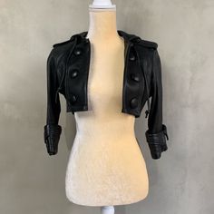 Cropped Genuine Leather Jacket With Hood And Black Button Detail. Excellent Pre-Loved Condition. Fitted Leather Cropped Jacket, Fitted Cropped Leather Outerwear, Fitted Cropped Black Biker Jacket, Fitted Black Leather Cropped Jacket, Elegant Black Leather Cropped Jacket, Fitted Leather Jacket With Buttons, Fitted Black Leather Jacket With Button Closure, Designer Fitted Leather Jacket With Buttons, Black Cropped Blazer With Button Closure