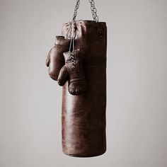 a pair of brown boxing gloves hanging from a chain