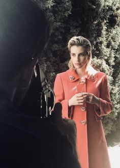 a woman in an orange coat is talking to someone