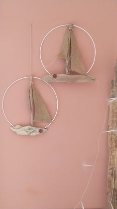 two small sailboats are hanging on the wall next to a piece of driftwood