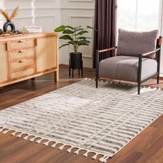 a living room area with a chair, rug and sideboard on the hardwood floor