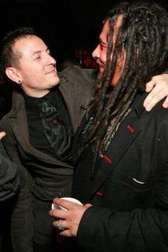 two men with dreadlocks are hugging each other at a party in the dark