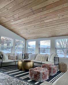 a living room filled with lots of furniture under a wooden ceiling mounted high up to the ceiling