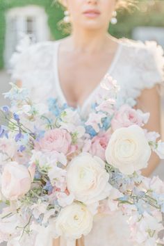 a woman holding a bouquet of flowers in her hands and wearing a white wedding dress