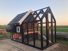 a small black house sitting in the middle of a field