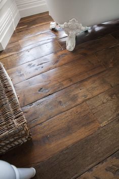 a bathroom with wood flooring and white trim on the walls, along with a wicker basket