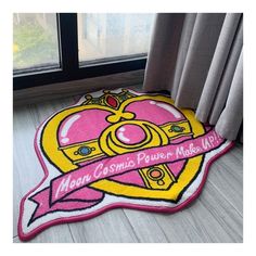 a pink and yellow rug with a crown on it in front of a large window