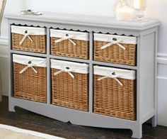 an old dresser with wicker baskets on the top and white trim around the drawers