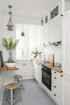 a white kitchen with wooden counter tops and stools next to the stove top oven