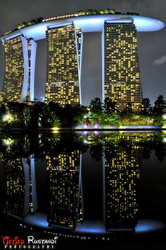 an image of a city at night with lights on the buildings and water reflecting in the foreground