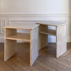 two tables sitting side by side on top of a wooden floor in front of a white wall