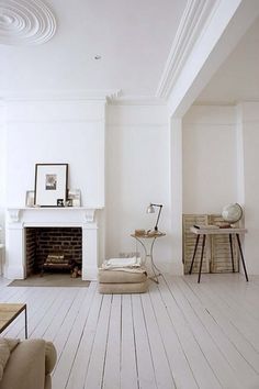 a living room with white walls and wood floors, including a fireplace in the center