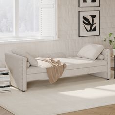 a living room with a white couch and books on the floor