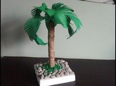 a small palm tree sitting on top of a table next to some rocks and pebbles