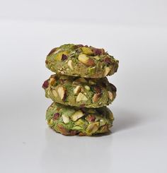 three cookies stacked on top of each other with nuts and pistachio toppings