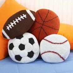 three crocheted balls with different designs on them sitting next to each other in front of an orange pillow