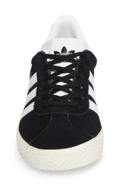 Initially designed as a training shoe for top athletes in 1991, the iconic adidas Gazelle sneaker has been refreshed with a sleek, narrower silhouette but retains the classic 3-Stripes and heel tab of the original. Lace-up style Removable OrthoLite® insole Leather and synthetic upper/textile and synthetic lining/rubber sole Imported Kids' Shoes Black Three Stripes Sneakers For Skateboarding, Black Basketball Shoes With Gum Sole For Sports, Black Basketball Shoes With Gum Sole, Adidas Sneakers For Skateboarding, Classic Black Skate Shoes With Three Stripes, Classic Black Sneakers With Three Stripes, Black High-top Skate Shoes With Three Stripes, Casual Black Sneakers With Three Stripes, High-top Tennis Sneakers With Laces