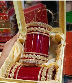 an open box with some red and gold jewelry in it's display case at a jewelery shop