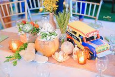 a table topped with lots of vases filled with flowers and plants next to candles